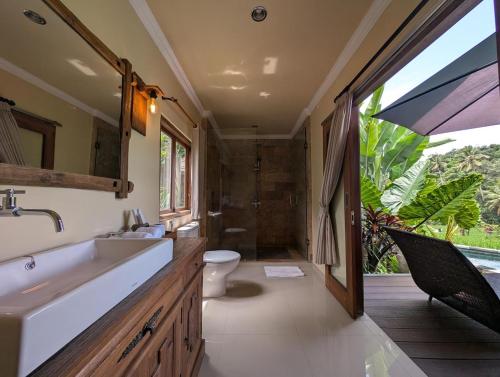 a bathroom with a sink and a toilet and a shower at Taksu Resort Ubud by Dhananjaya Hospitality in Ubud
