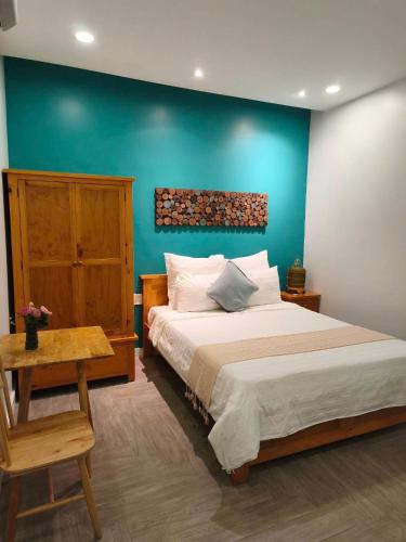 a bedroom with a large bed with a blue wall at Homestay Hoàng Thi in Phan Thiet