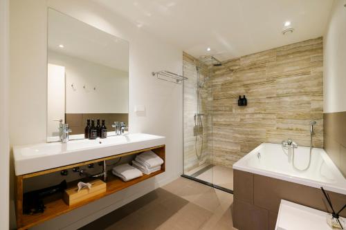 a bathroom with two sinks and a tub and a shower at Bloemendaal Hotel Collection Apartments in Bloemendaal