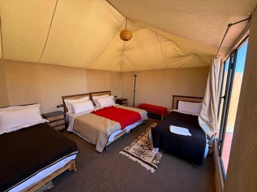 a room with two beds in a tent at Isma Luxury Camp in Merzouga