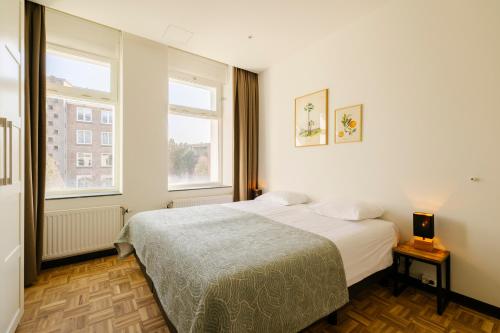 a bedroom with a bed and two windows at Bloemendaal Hotel Collection Apartments in Bloemendaal