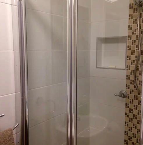 a shower with a glass door in a bathroom at Dees Front Studio Room in Hazelbrook