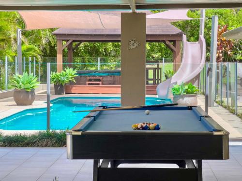 a pool table in front of a swimming pool at Solis Acreage Escape in Advancetown