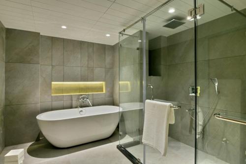 a bathroom with a tub and a glass shower at Kratos Lifestyle in Surat