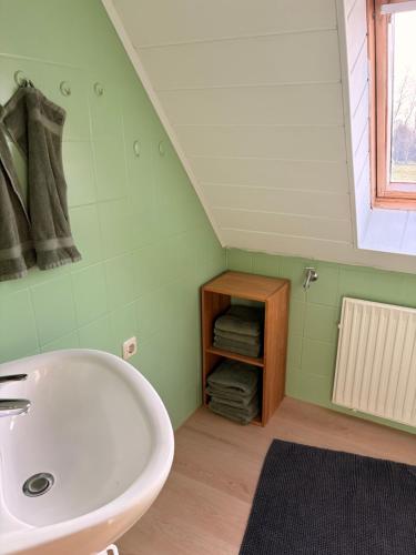 a bathroom with a sink and a shelf with towels at Ferienwohnung Weitblick in Großheide
