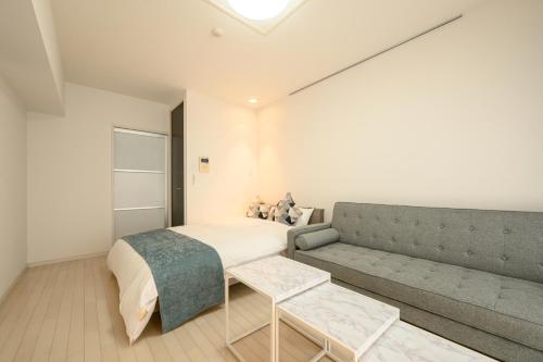 a bedroom with a bed and a couch at Wilshire APT ホテル in Miyazaki