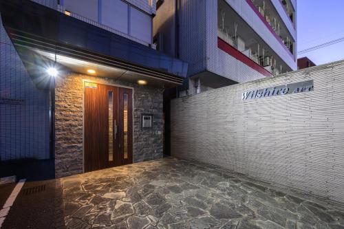 a entrance to a building with a wooden door at Wilshire APT ホテル in Miyazaki