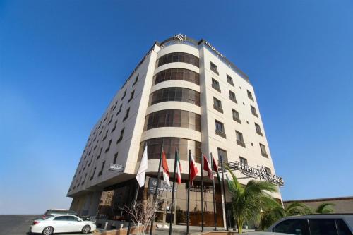 a tall white building with flags in front of it at Friesian Hotel Apartments in Jeddah