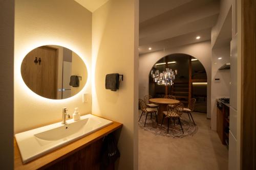 a bathroom with a sink and a table with chairs at SUNZ ROOMS -naha miebashi- in Naha