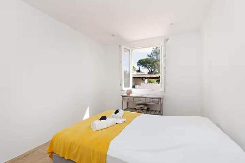 a white bedroom with a bed with a yellow blanket at Les cinq soleils in Roquebrune-sur-Argens