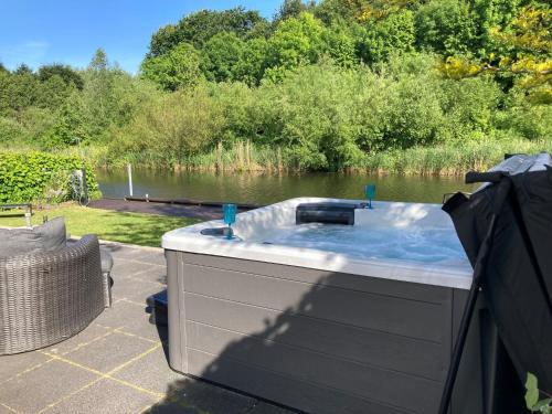 a hot tub sitting on a patio next to a body of water at Scandinavisch Nr. 221 | 8 Pers. Jacuzzi in Zeewolde
