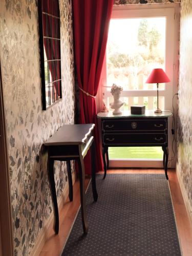 a room with a desk and a window with a red curtain at Le Clos Lauradière in Cormeilles