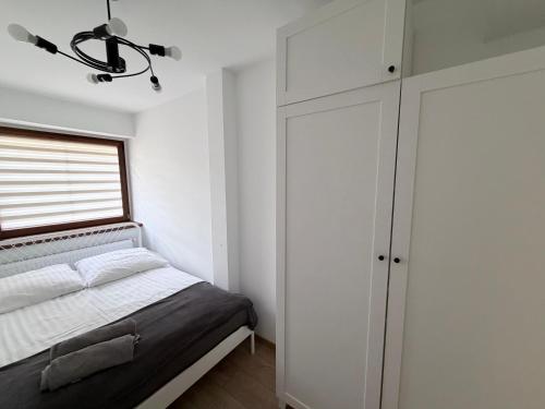 a white bedroom with a bed and a window at Piast Castle Apartment Brzeg in Brzeg