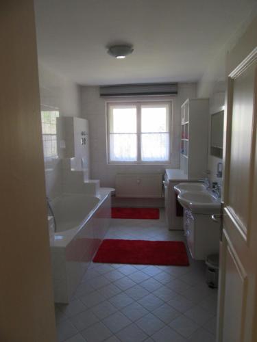 a bathroom with two sinks and a tub and a window at Ferienwohnung Alpenvilla in Bischofswiesen
