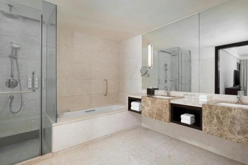 a bathroom with a shower and a tub and a sink at Courtyard by Marriott Hangzhou Wulin at West Lake in Hangzhou