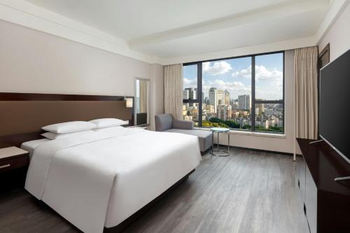a bedroom with a large white bed and a large window at Courtyard by Marriott Hangzhou Wulin at West Lake in Hangzhou