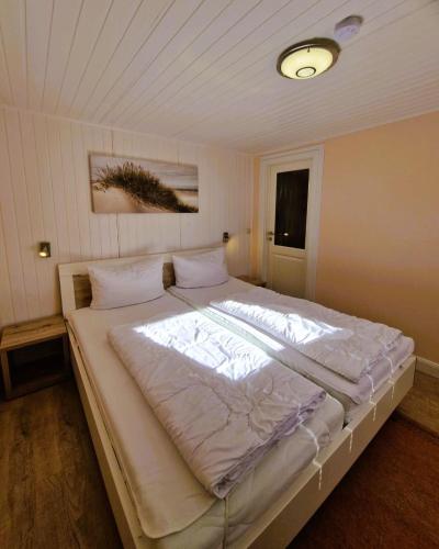 a large white bed in a bedroom with a ceiling at Haegerende _Alte Liebe_ in Groß Kirr