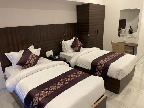 a hotel room with two beds and a mirror at Hotel Mahavir in Ankleshwar