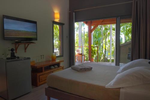 a bedroom with a large bed with a television on the wall at Lodge Palmae - Lodge de charme avec Jacuzzi Privatif en Option - Adults Only in Saint-Pierre