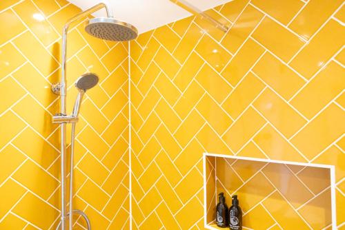 a yellow bathroom with a shower and a mirror at Pear Tree Cabin in Whitstable