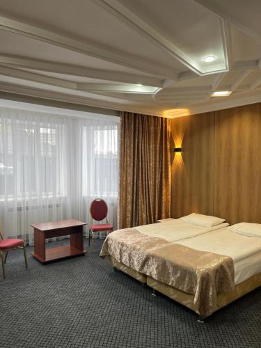 a hotel room with a large bed and a table at Aq-Jaiyq Halal Hotel in Karagandy