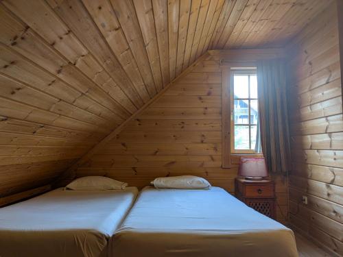 two beds in a wooden room with a window at Chalé 24 in Penhas da Saúde
