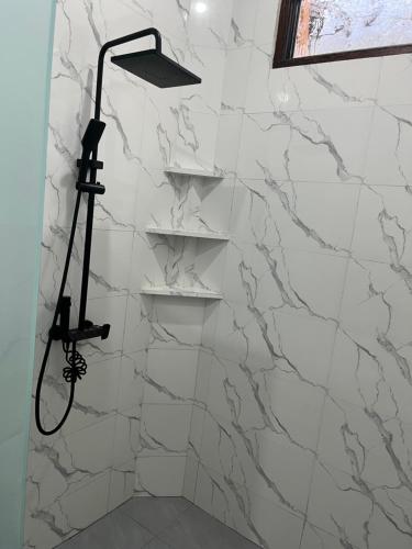 a shower with white marble walls and a shower head at JS Guest House in Seminyak