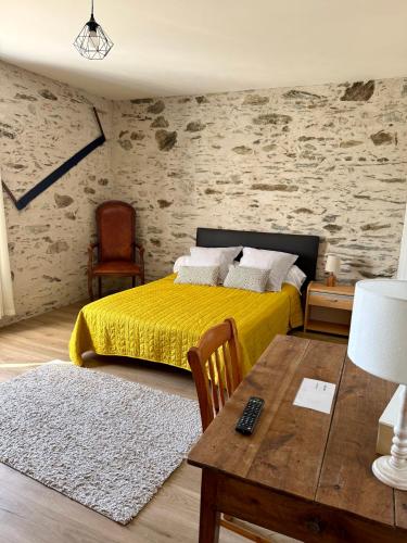 a bedroom with a yellow bed and a table at Chambre d´hôtes La Jonchère in Les Herbiers
