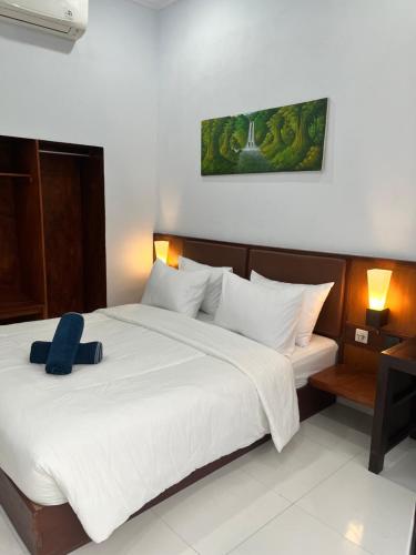 a bedroom with a large bed with a blue pillow on it at JS Guest House in Seminyak