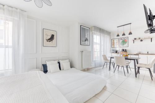 a white bedroom with a bed and a dining room at L'Écrin Piano, chic near Paris in Asnières-sur-Seine