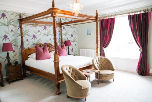 a bedroom with a four poster bed and two chairs at The Ollerod in Beaminster