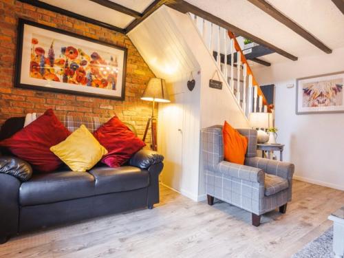 a living room with a leather couch and a chair at Y Bwythyn - Lovely cottage in village of Spittal in Haverfordwest