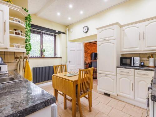 a kitchen with white cabinets and a table and chairs at Y Bwythyn - Lovely cottage in village of Spittal in Haverfordwest