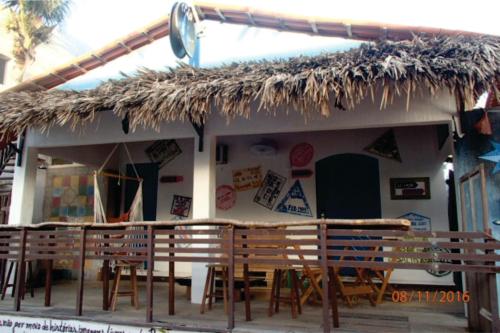 uma cabana com cadeiras e um telhado de palha em Trip Bar Hostel em Jericoacoara