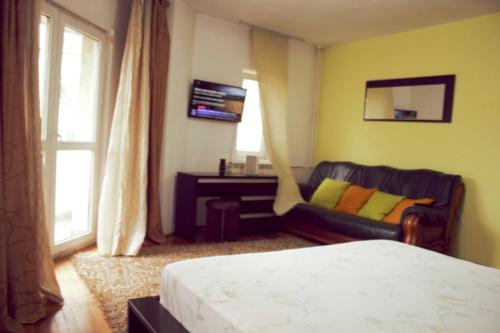 a bedroom with a bed and a couch and a window at decebal premium apartment in Bucharest