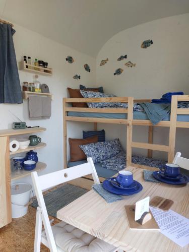 a room with bunk beds and a table with blue dishes at Schäferwagen Gartenblick Nr 4 in Radebeul