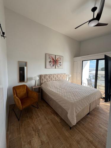 a bedroom with a large bed and a chair at Loveli Stay Aruba in Oranjestad