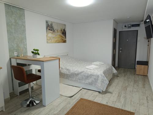 ein Schlafzimmer mit einem Bett und einem Schreibtisch mit Stuhl in der Unterkunft Harmony Studio in Târgu Secuiesc