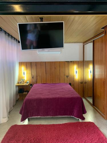 a bedroom with a purple bed with a flat screen tv at Loft com piscina, sauna e hidro in Niterói