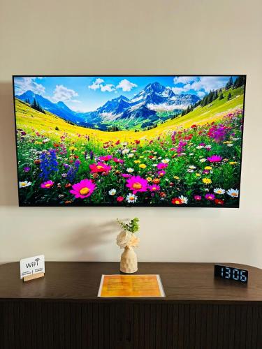 a flat screen tv hanging on a wall with flowers at Caro Studio in Tunari