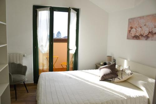 a bedroom with a large white bed and a chair at Casa Sole - holiday apartment in Maccagno Superiore