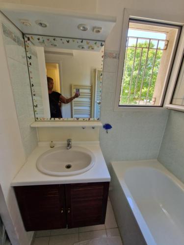 Ein Mann fotografiert ein Badezimmer mit Waschbecken in der Unterkunft Studio DOUILLET in Aix-en-Provence