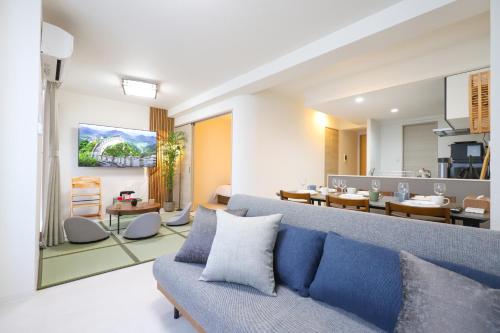 a living room with a blue couch and a dining room at Urna Sands Hotel in Tokyo