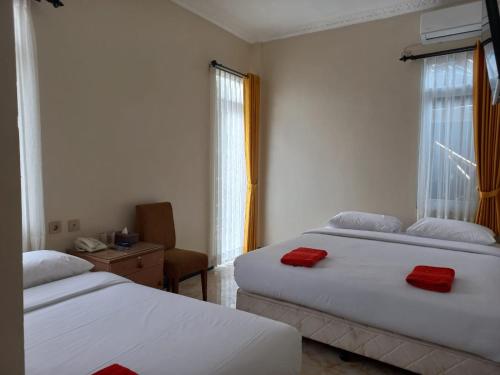 a bedroom with two beds with red towels on them at Dago Hotel Salon FORA in Bandung