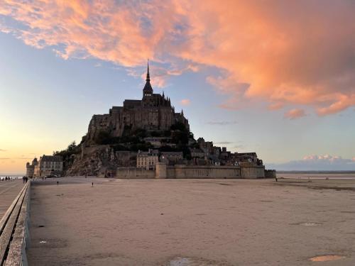 an island on the beach with a cloudy sky at Cottage Le Phare in Mont-Dol
