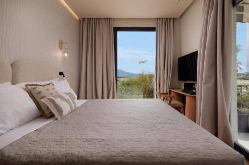 a bedroom with a large bed and a large window at Avia in Corfu