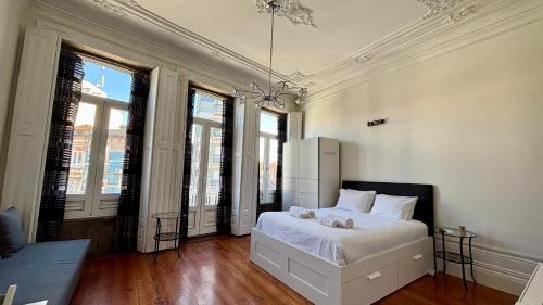a bedroom with a bed with white sheets and windows at Pombeiro Apartments in Porto