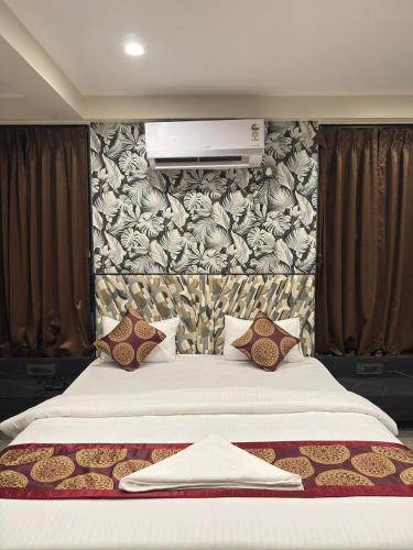 a bedroom with a large white bed with a wall at Hotel SK Chakan Pune in Dehu
