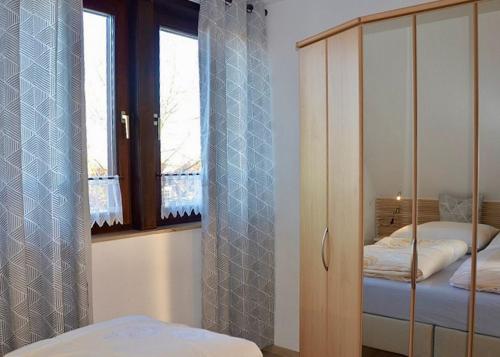 a bedroom with two beds and a cabinet and windows at Ferienwohnung Bolle in Hooksiel
