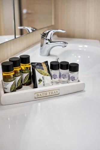 a bathroom counter with a sink with four bottles of toiletries at Haroupia The Residence in Kalidhón